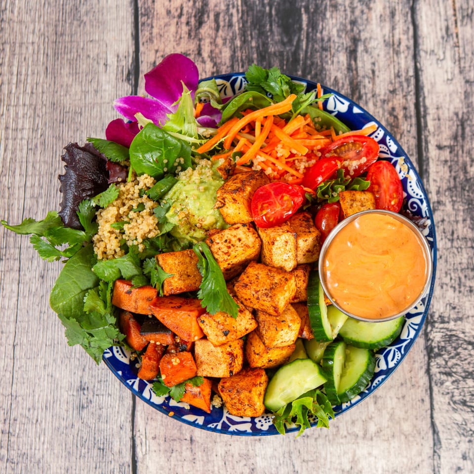 A Lo Fresco healthy bowl with tofu, sweet potatoes, quinoa, vegetables, and a side of sauce.