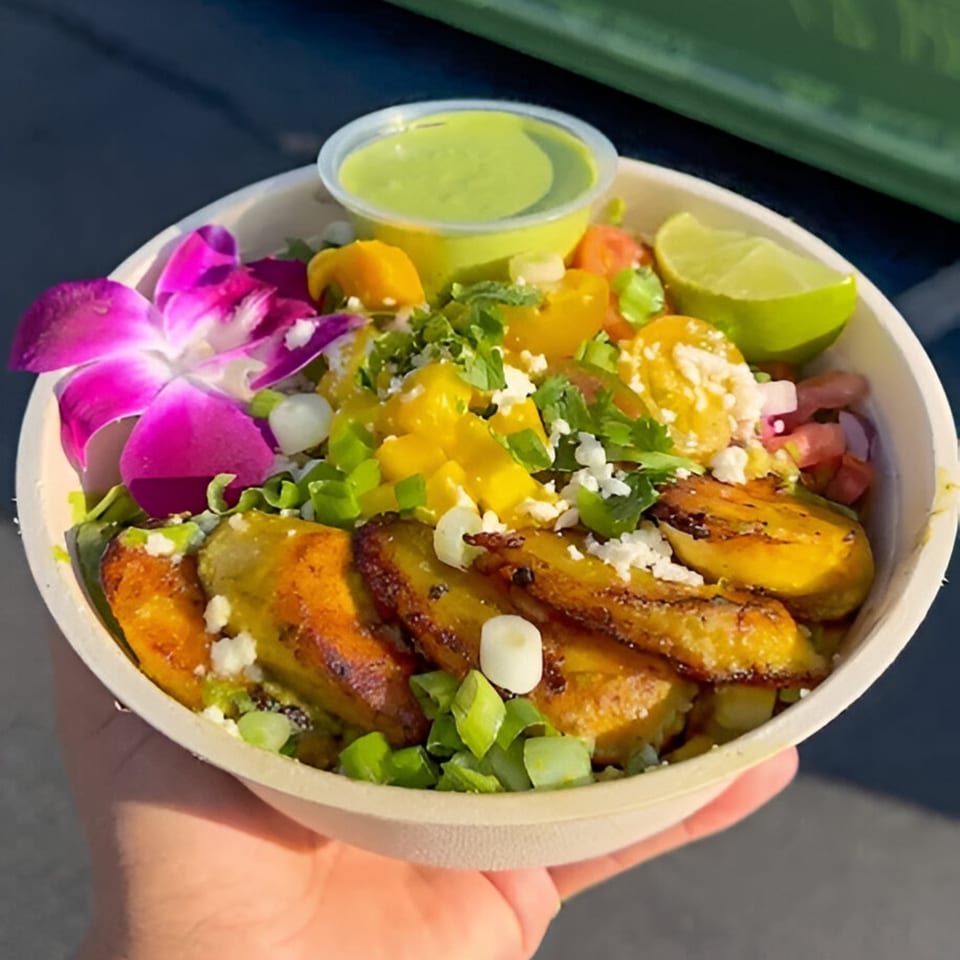 A Lo Fresco's healthy bowl with plantains, mango, lime, and a purple orchid garnish.